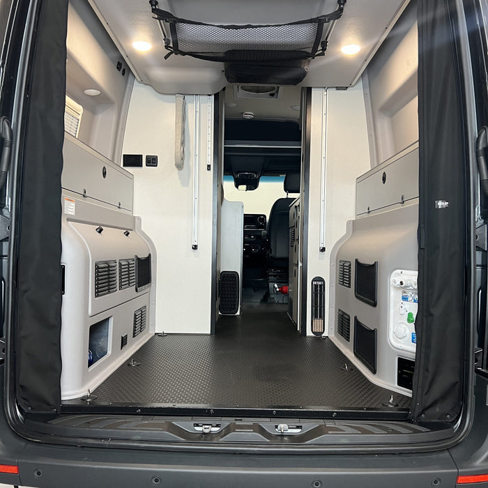Revel bed harness cover installed in rear van interior with folded sleeping platform and storage compartments.