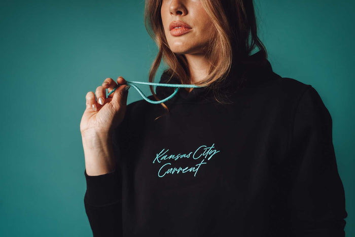 Unisex Black Teal Script Hoodie Zoomed In on Model