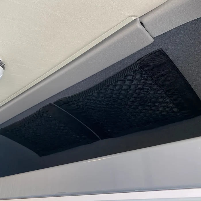 Black mesh storage net mounted on interior ceiling panel of a van.