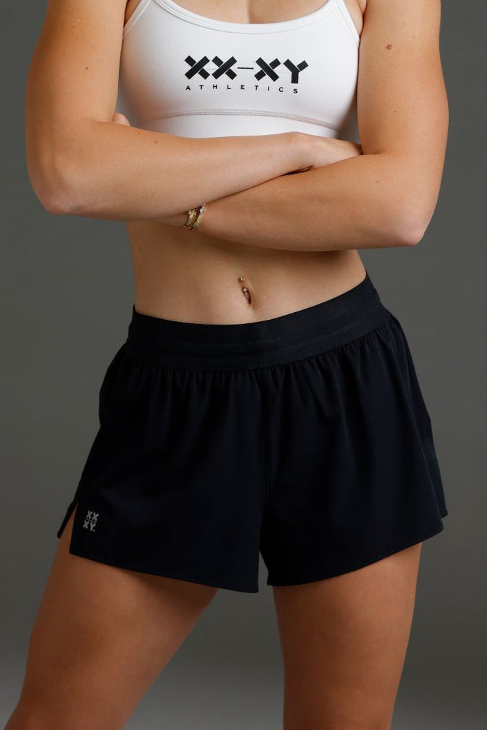 Person wearing a white sports bra and black shorts with 'XXY Athletics' branding || Black