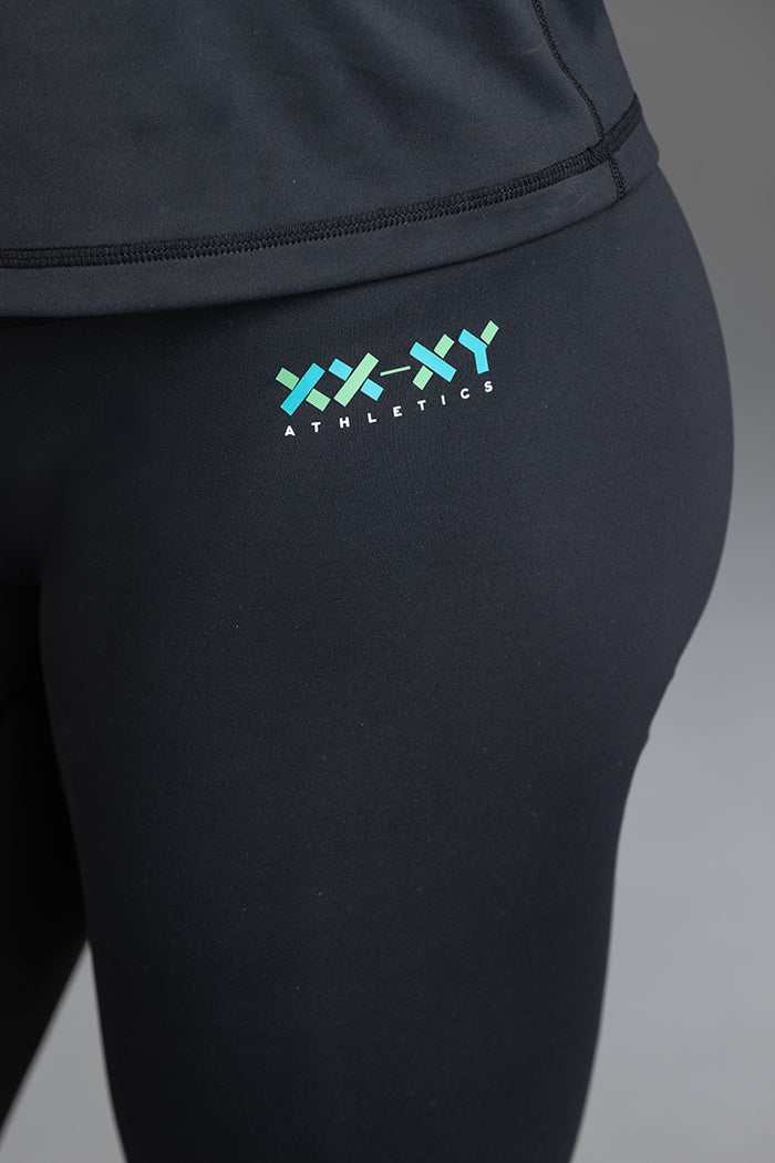 Black athletic leggings with a logo on the leg against a gray background || Black