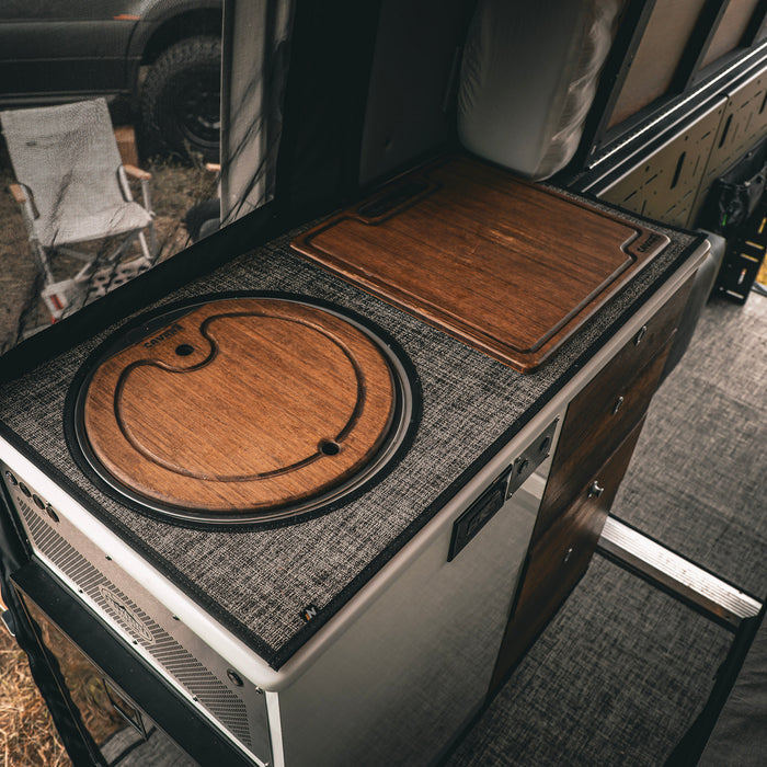 Revel bamboo sink cover in van kitchen with textured countertop and wood cabinetry