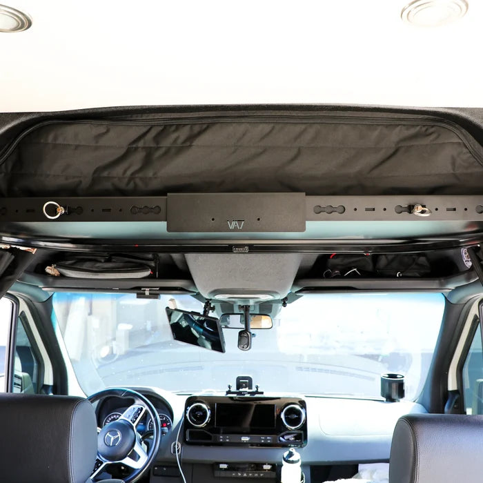 GH1 cab shelf TV bracket mounted above driver area in van interior with storage and wiring access.