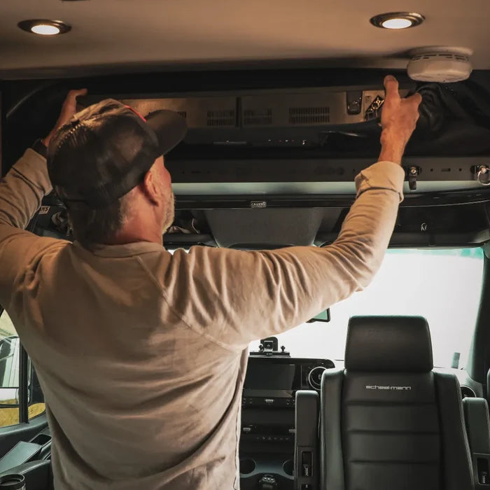 Man installing Cab Shelf TV Bracket in overhead storage area of a van interior