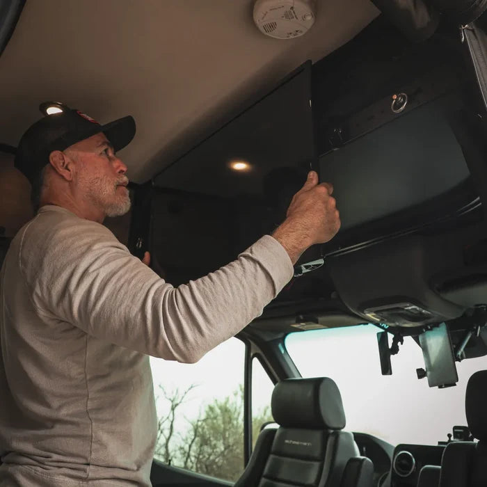 Man installs Cab Shelf TV Bracket near ceiling in van cab area