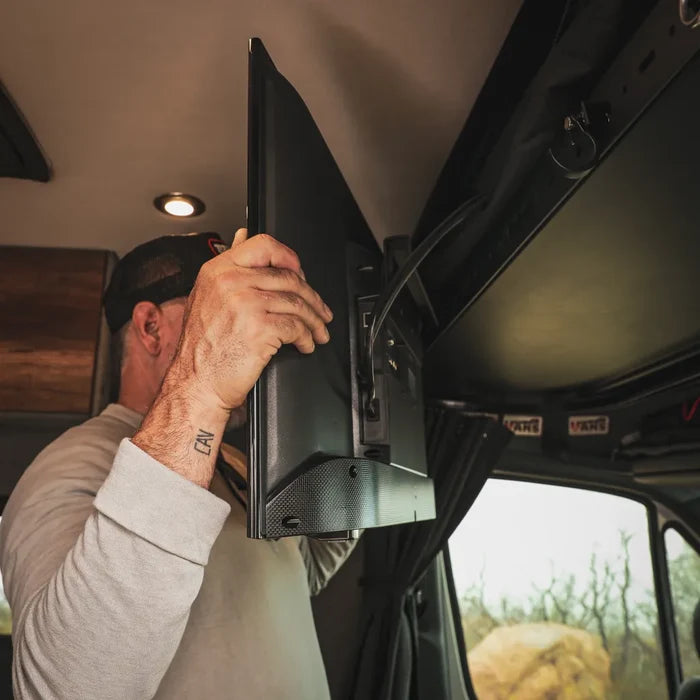 Man installing a Cab Shelf TV Bracket in a van interior with overhead shelf.