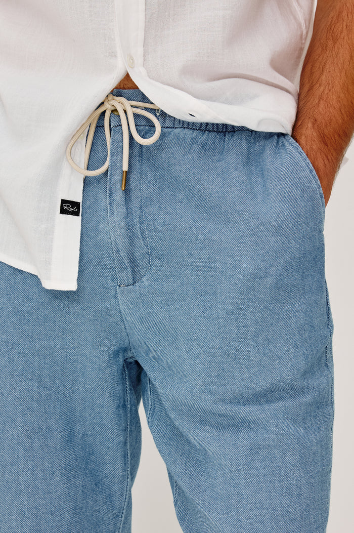 Callum Tapered Straight Leg Pant in Linen Twill With Adjustable Drawstring Waistband Ties in Medium Wash Indigo Colorway - Lower Body Front View Featured on Model