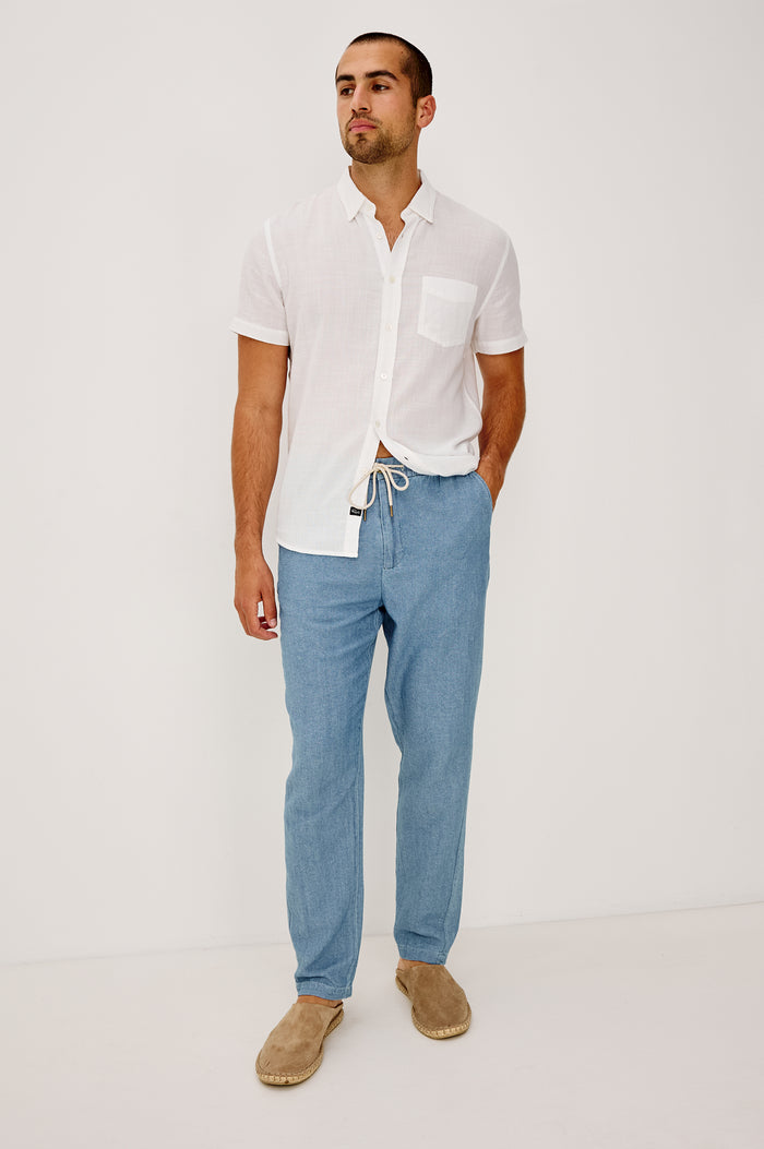 Callum Tapered Straight Leg Pant in Linen Twill With Adjustable Drawstring Waistband Ties in Medium Wash Indigo Colorway - Full Body Front View Featured on Model