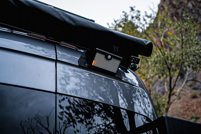 Canyon Motion Sensor Solar Light mounted on the rear roof rack of a van in a wooded area