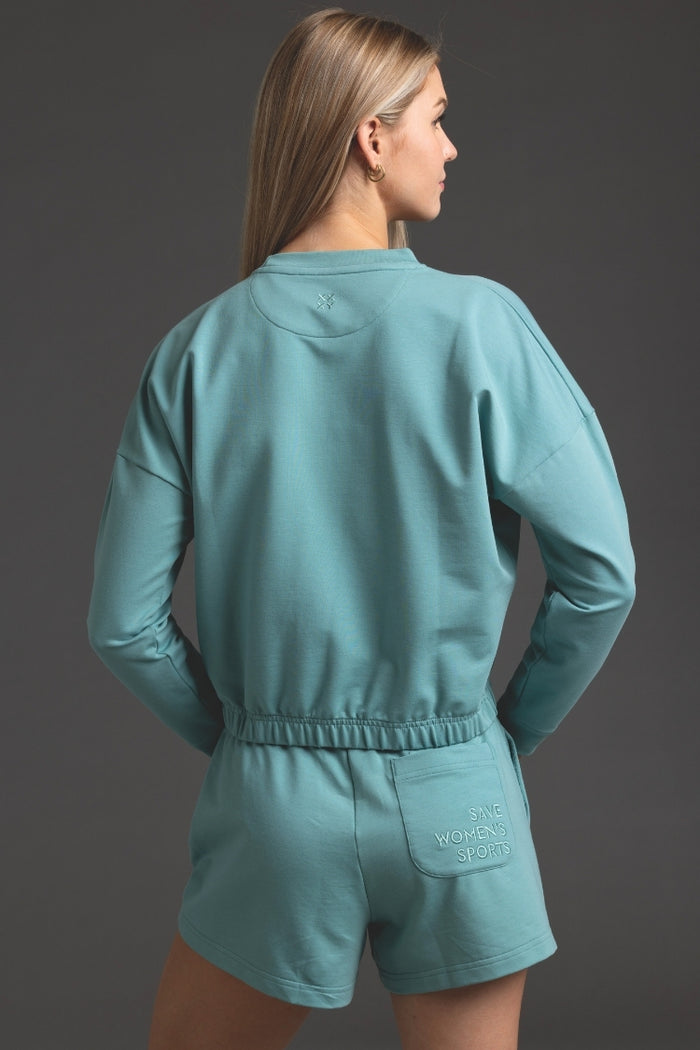 Person wearing a teal outfit with 'Ninety Percent' branding on a gray background || Underseas