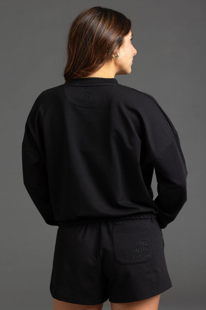 Person wearing a black outfit with text on shorts against a gray background || Black