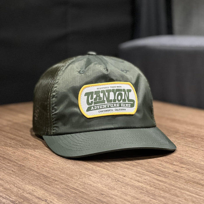 Green Talon Chatsworth Hat with mesh back and logo patch on wood surface