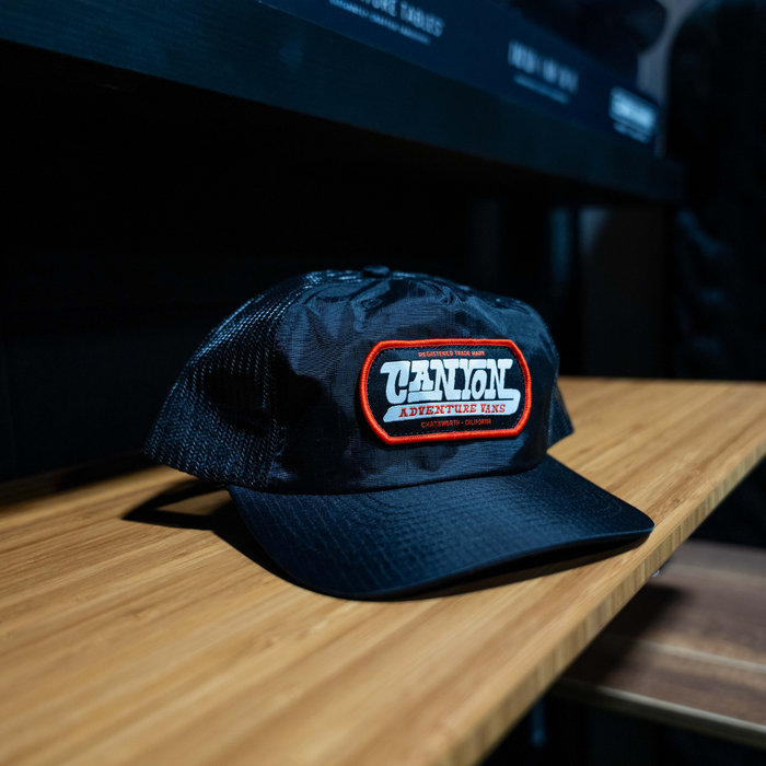 Black Chatsworth Hat with Canyon Adventure Vans patch on wooden surface