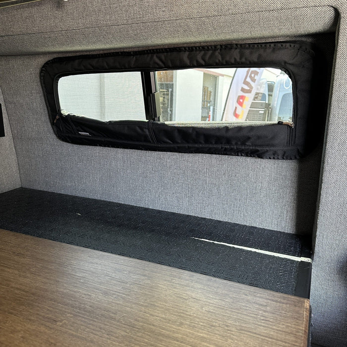 Revel CLIMA-SHADE van window cover installed on interior wall above a dark wood table.