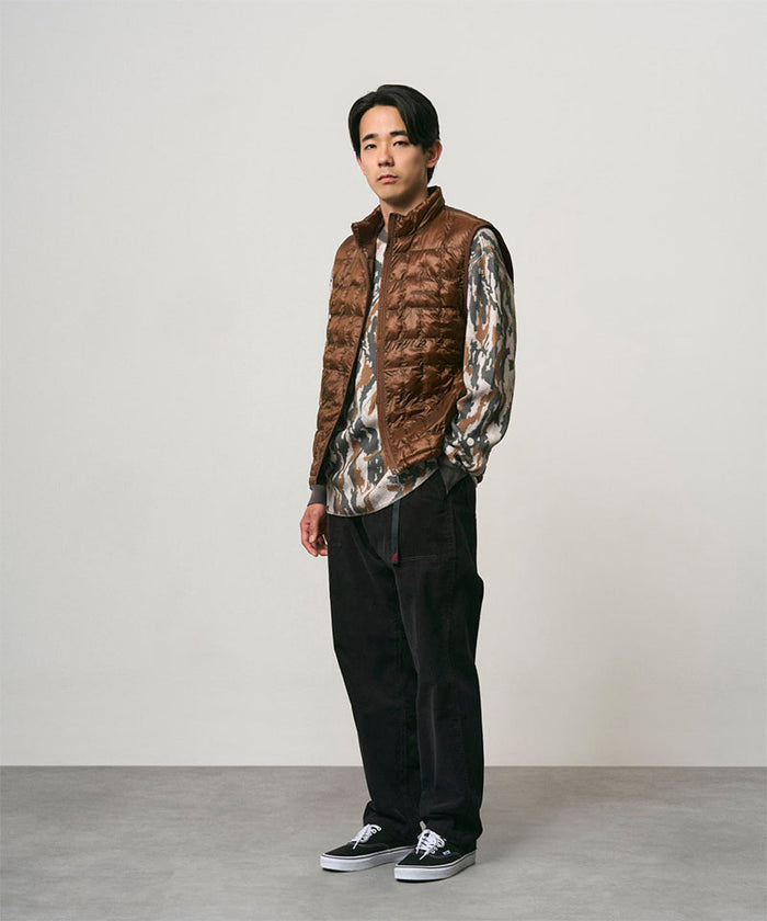 Model wearing black Gramicci Corduroy Loose Tapered Ridge Pants and a brown vest on a light-tone background.