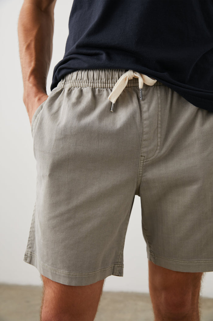 Cruz Shorts with a Drawstring Waist, Two Front Pockets, Two Back Button Flap Pockets in Washed Grey Colorway - Front View Featured on Model