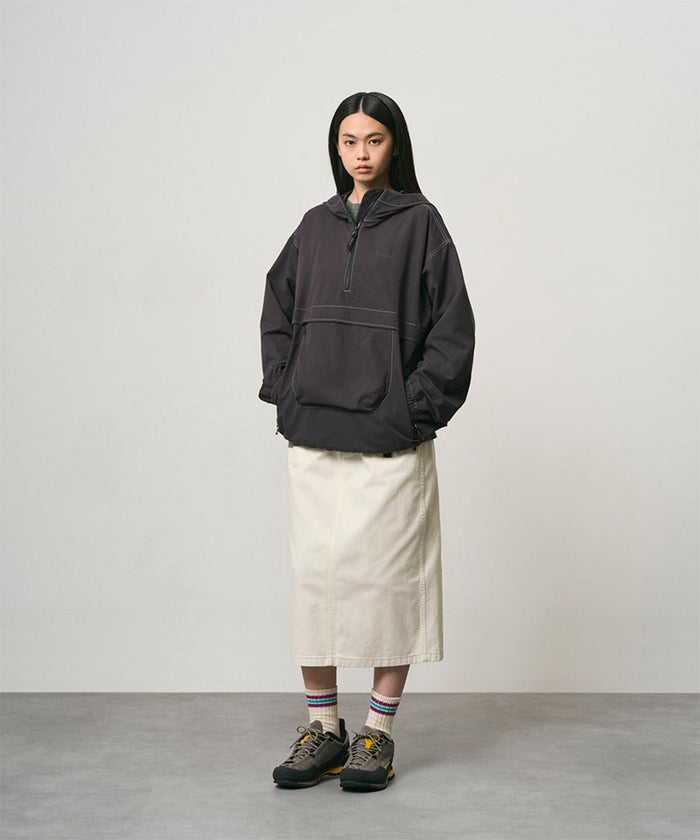 Model wearing a bone colored Gramicci Denim Carpenter Skirt and a dark brown jacket on a light-tone background.
