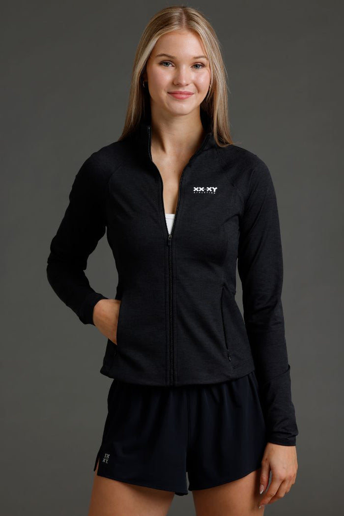 Woman wearing a black tracksuit with a logo on a gray background || Black