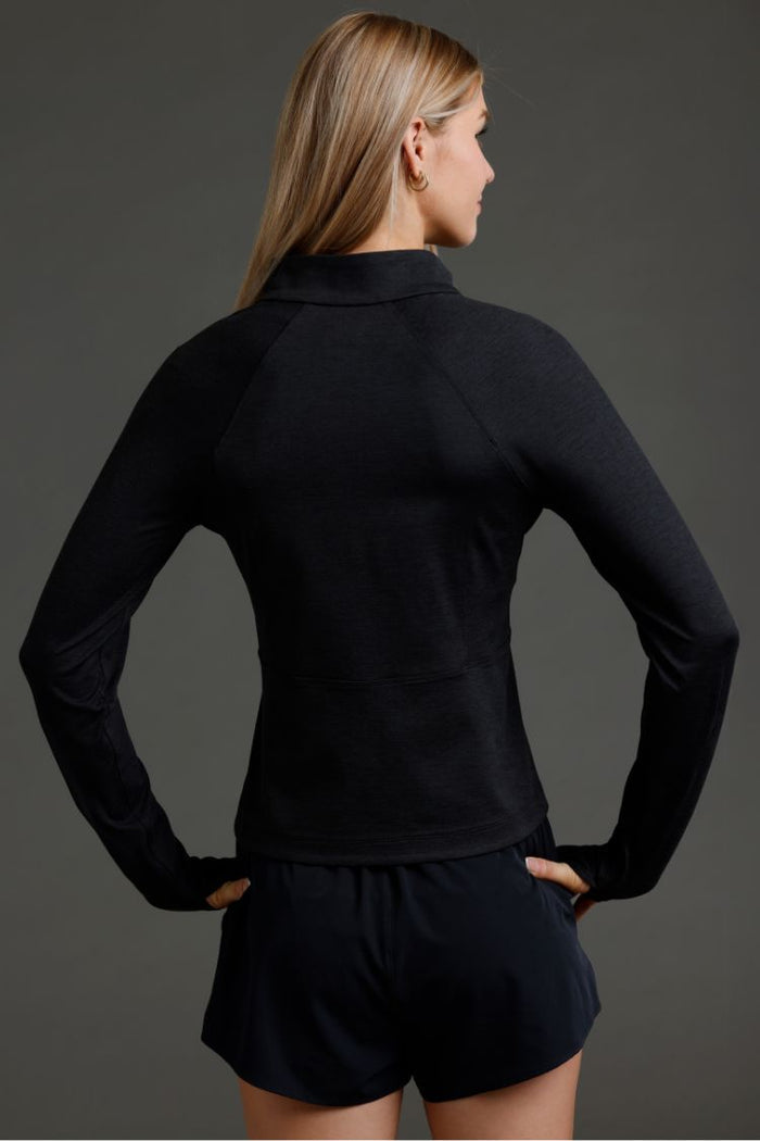 Person wearing a black long-sleeve top and shorts on a gray background || Black