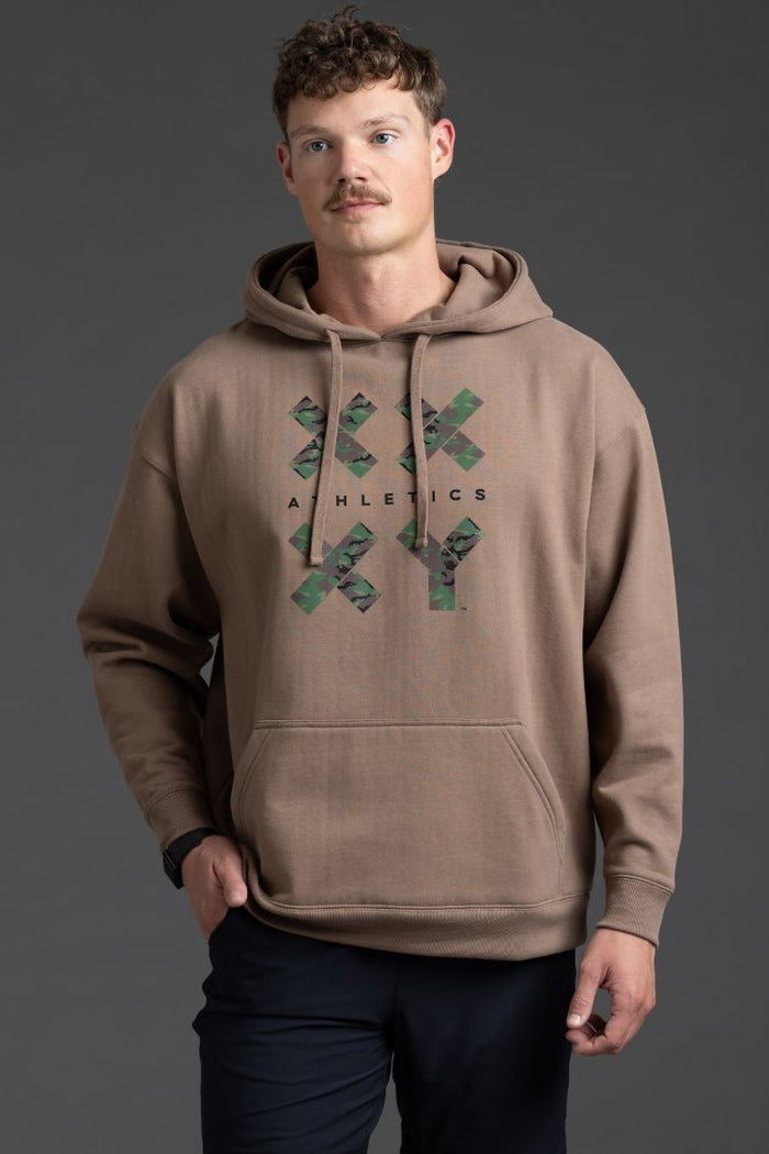 Man wearing a brown hoodie with a logo on a gray background || Mocha