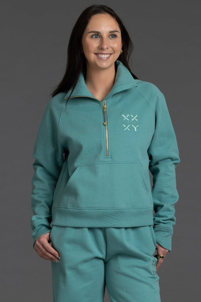 Woman wearing a teal tracksuit with a logo on a gray background || Underseas