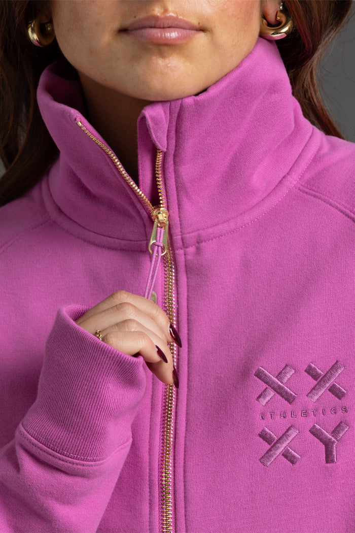 Close-up of a person wearing a pink hoodie with a brand logo on the chest. || Bright Fuchsia