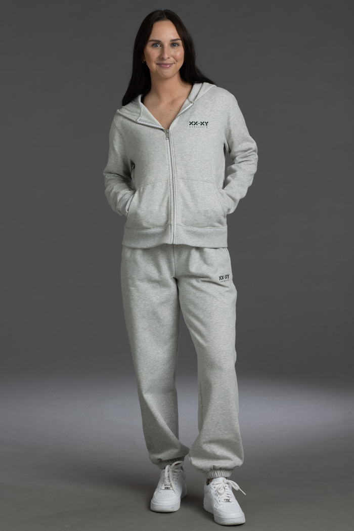 Woman wearing a gray tracksuit with a brand logo on a gray background || Light Heather Gray