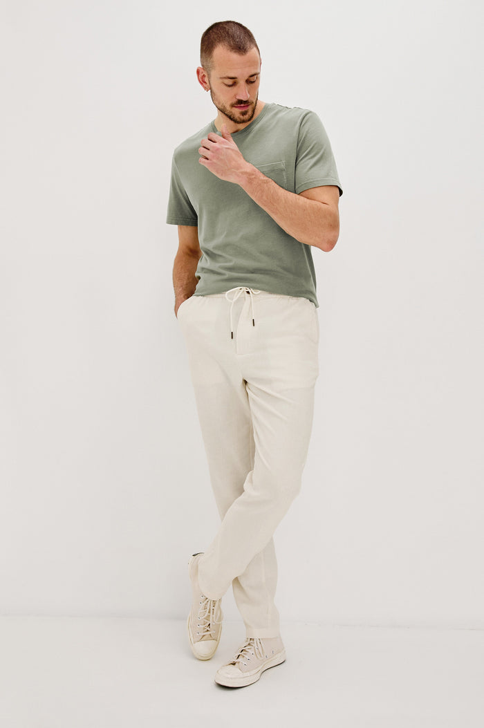 Johnny Short Sleeve T-Shirt with a Crew Neck, Chest Patch Pocket and Small Slits at the Side Hems in Olive Colorway - Full Body Front View Featured on Model