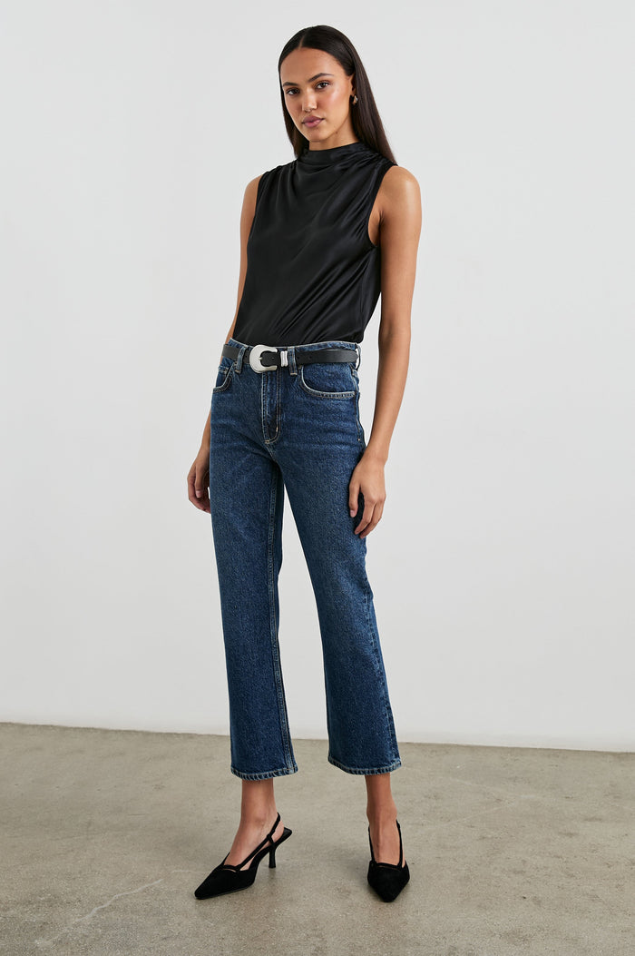 Kaleen Sleeveless Top with Mock Neck with Buttons and Keyhole on the Back and Draped Fabric on the Upper Chest in Ivory Colorway- Front Tucked Full Body View Featured on Model