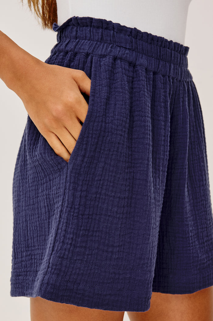 Leighton Short in Double Gauze With High-Rise, Smocked Elastic Waistband, Relaxed Fit, and Side Pockets in Admiral Blue Colorway - Lower Body Side View Featured on Model