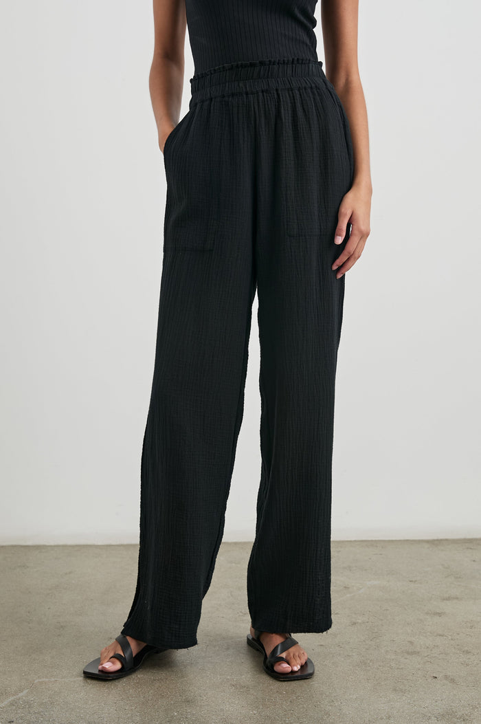 Leon Pant with a Smocked Waistband, Short Side Slits on Outer Leg and Two Front Seam Pockets in Black Colorway - Front View Featured on Model