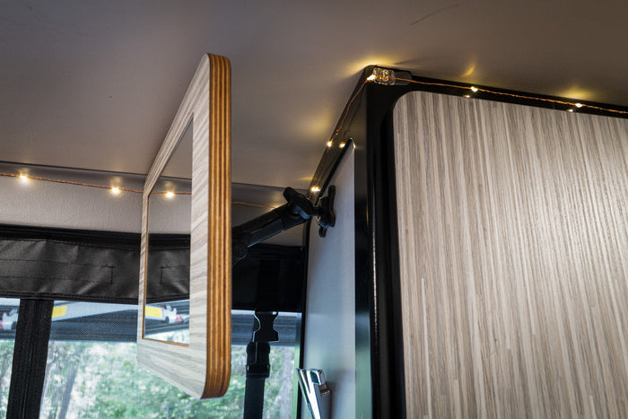Revel Mount-Anywhere Mirror Kit attached to van wall near ceiling with flexible arm and wood frame.