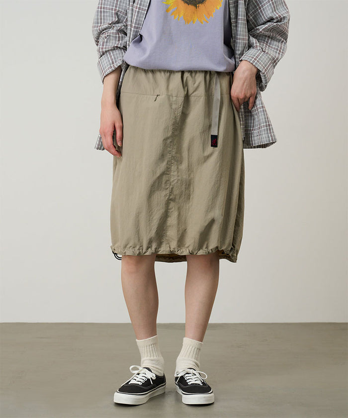 Model wearing a Gramicci milk tea colored Nylon Packable Midi Skirt against a light-tone background.