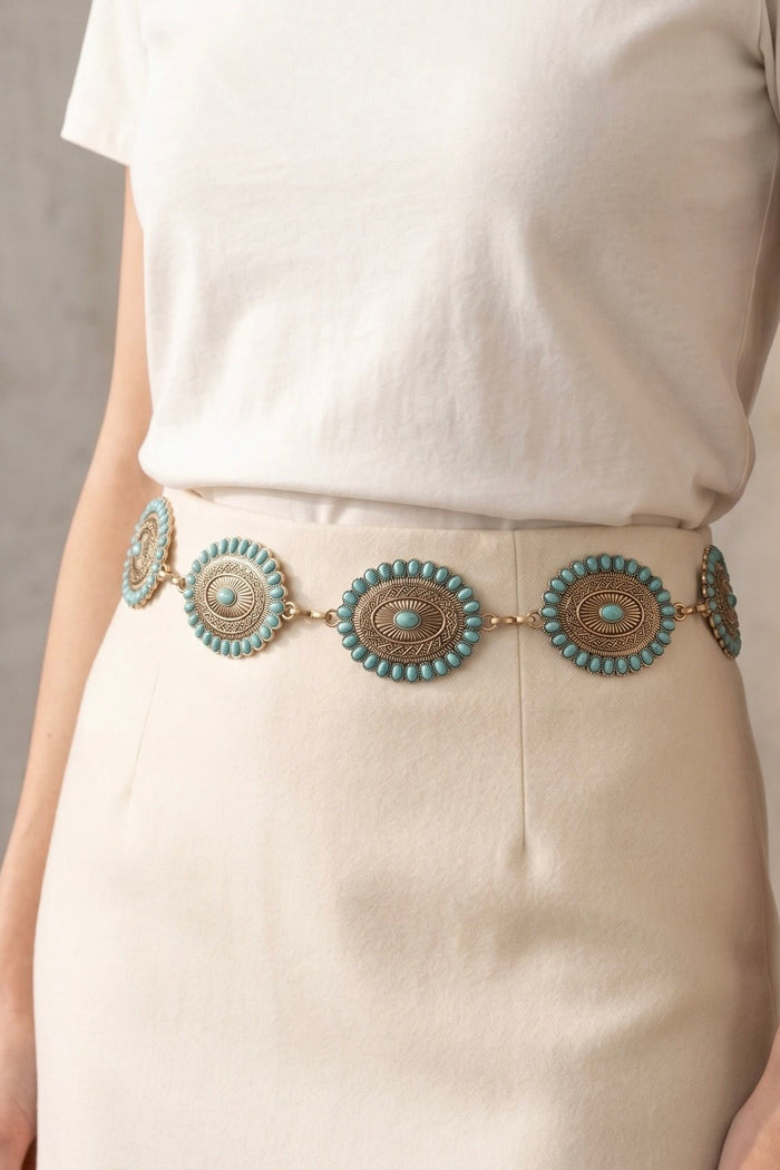 Western chain belt with antique gold oval conchos featuring turquoise stud accents, styled around a white skirt for a classic cowgirl-inspired look.