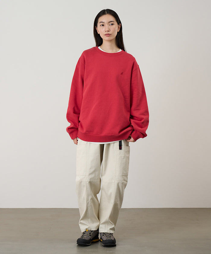 Model wearing a crimson red Gramicci One Point Crew Sweatshirt and beige pants on a light-tone background.