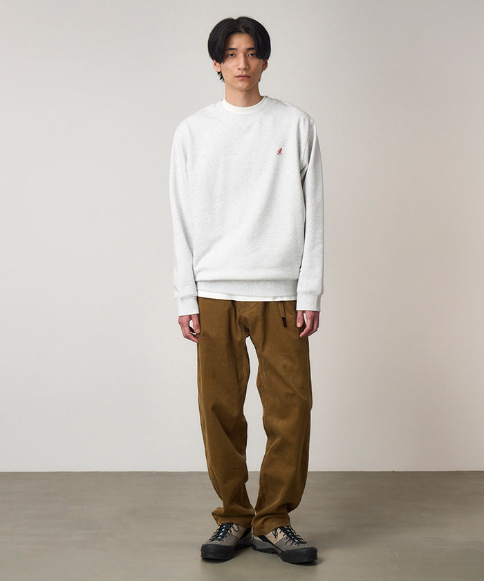 Model wearing a heather ash Gramicci One Point Crew Sweatshirt and brown pants on a light-tone background.