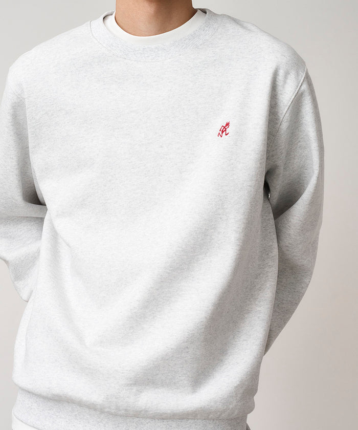 Model wearing a Gramicci heather ash One Point Crew Sweatshirt against a light-tone background.
