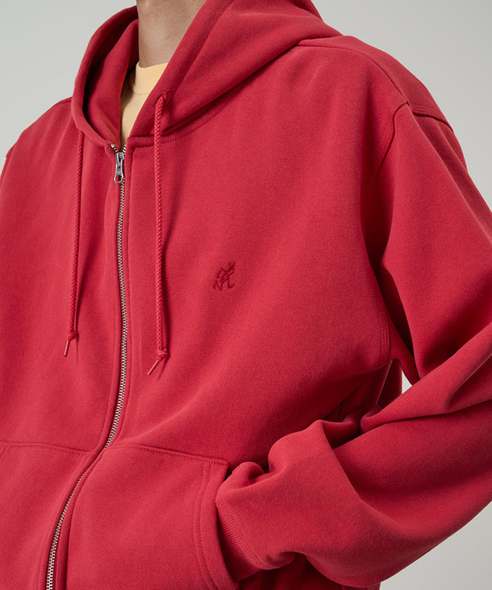 Model wearing a Gramicci crimson red One Point Zip Hooded Sweatshirt against a light-tone background.