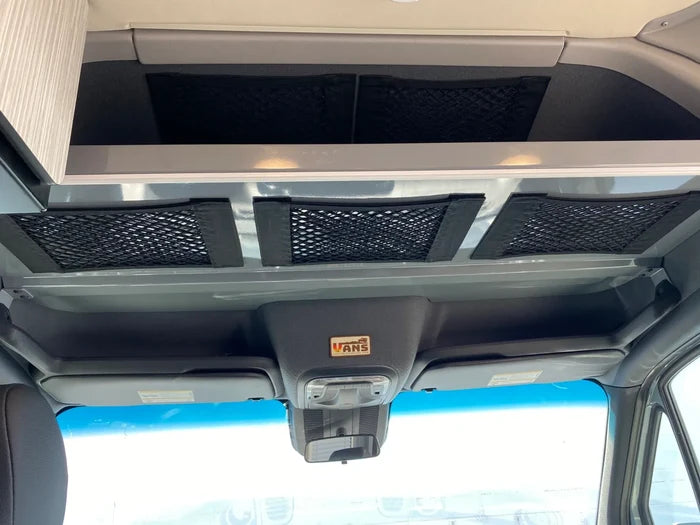 Overhead storage net installed in front cab area of a van, featuring black mesh and support straps.