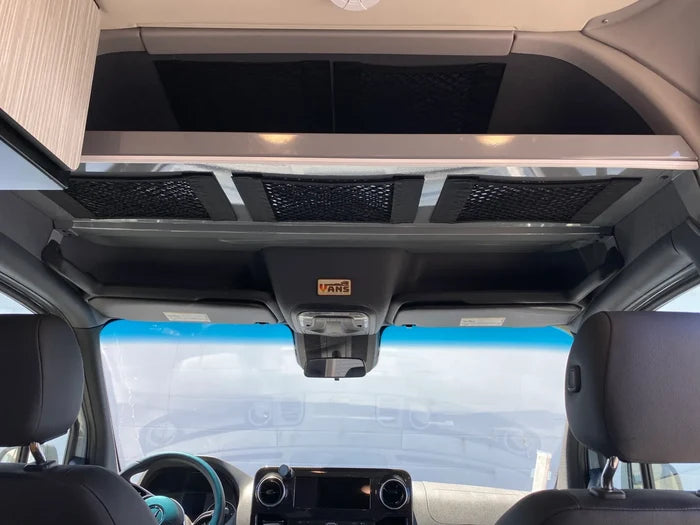 Overhead storage net above driver cab in van interior with black mesh compartments.