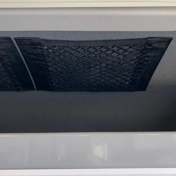 Black mesh storage net mounted on van interior wall for compact organization.