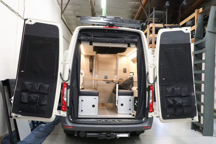 Rear view of a van with the DOORGANIZER storage system on both open back doors and a modern seating area inside.